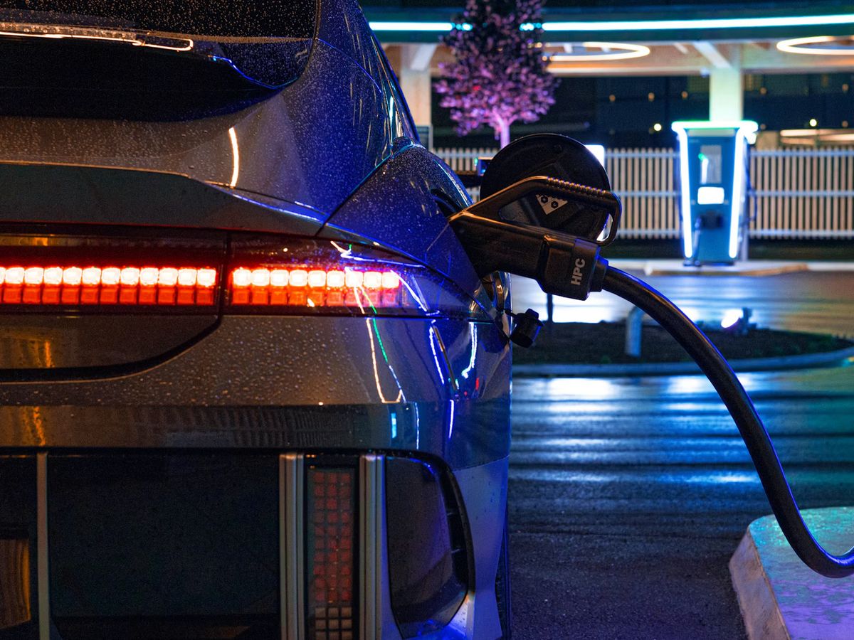 An electric car plugged into a rapid charger at night