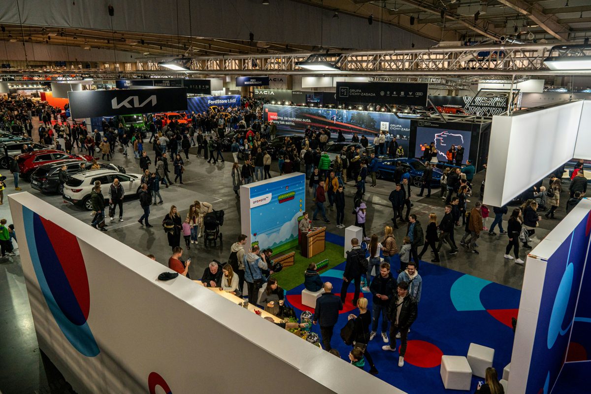 Crowds walking between car stands in a busy motor show hall